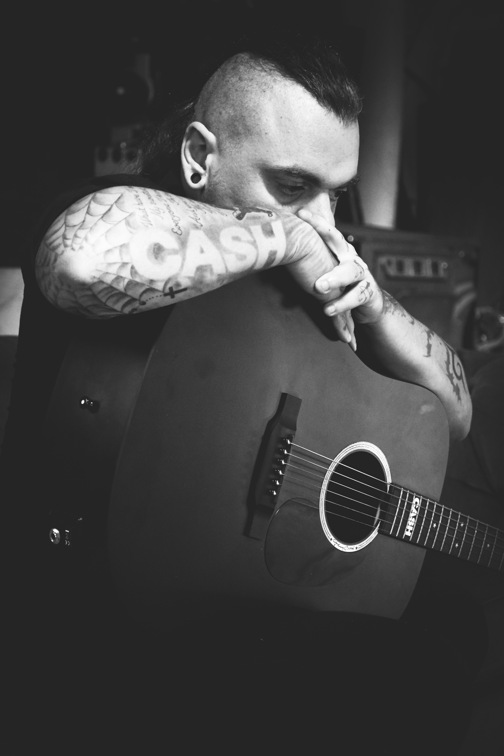 Portrait de Walk The Line, guitare en main et tatouage CASH visible